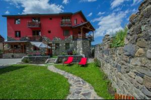 una casa rossa con due sedie rosse e un muro di pietra di RED HOUSE a Bakuriani