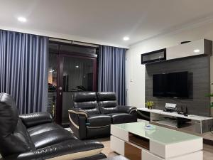 uma sala de estar com cadeiras de couro preto e uma televisão em Riverbank Suite @ Waterfront KCH em Kuching