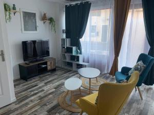 salon z dwoma stołami i telewizorem w obiekcie Appartement avec cours w mieście Gien