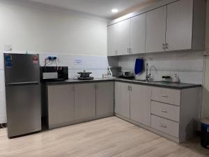 a kitchen with white cabinets and a stainless steel refrigerator at Riverbank Suite @ Waterfront KCH in Kuching