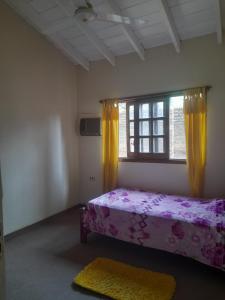 1 dormitorio con 1 cama y una ventana con cortinas amarillas en La casa de Moni, en Areguá
