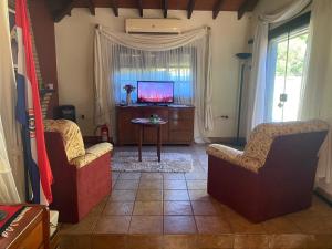 sala de estar con 2 sillas y TV en La casa de Moni, en Areguá