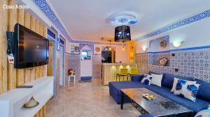 un salon avec un canapé bleu et une télévision dans l'établissement Casa Amine, à Chefchaouen