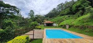 una piscina en un jardín con una casa en Sitio Santa Clara, en Teresópolis