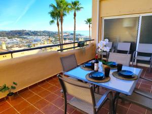 einen Tisch und Stühle auf einem Balkon mit Palmen in der Unterkunft Duplex - Fantastic Urbanization Las Terrazas de Cala Mijas in La Cala de Mijas