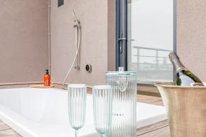 tres copas de vino sentadas en un mostrador junto a una bañera en Love Nest - Your cosy penthouse en Ostende