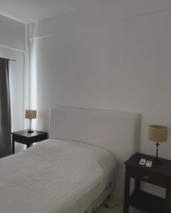 a bedroom with a white bed and two night tables at Departamento Moritan in Posadas