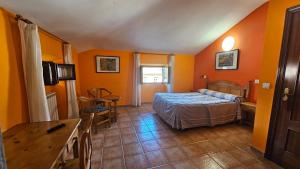 1 dormitorio con paredes de color naranja, 1 cama y 1 mesa en HOSTAL ALBE, en Carrión de los Condes