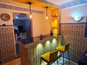 une cuisine avec un bar et 2 chaises jaunes dans l'établissement Casa Amine, à Chefchaouen