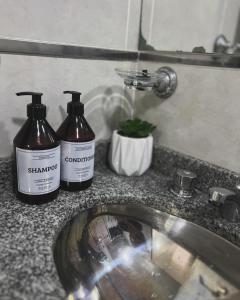 two bottles of shampoo sitting on a counter next to a sink at Departamento Moritan in Posadas