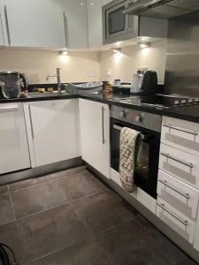 a kitchen with white cabinets and an oven with a towel at 1 Bed flat in Central London in London