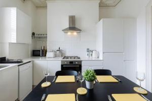 a kitchen with a black table with yellow napkins and wine glasses at Stylish period maisonette flat in centre of Bath in Bath