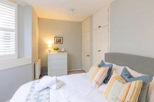 1 dormitorio con cama blanca y almohadas coloridas en Stylish period maisonette flat in centre of Bath en Bath