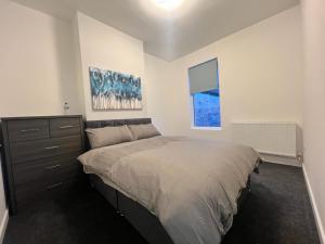 1 dormitorio con 1 cama, vestidor y ventana en 4 bedroom, sleeps 8 comfy home near to City Centre and Beaches!, en Swansea
