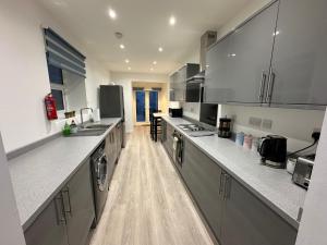 cocina grande con electrodomésticos de acero inoxidable y suelo de madera en 4 bedroom, sleeps 8 comfy home near to City Centre and Beaches!, en Swansea