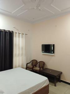 a bedroom with a bed and two chairs and a tv at Holy Homestay in Faizābād