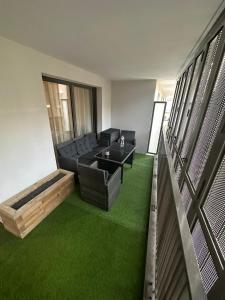 un soggiorno con divano nero e erba verde di JO Appart Paris Summer ad Aubervilliers