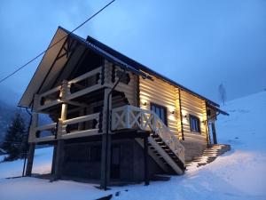 eine Blockhütte im Schnee mit Licht in der Unterkunft White House in Synewyrska Poljana