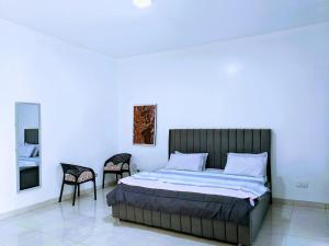 um quarto com uma cama e duas cadeiras em Homestay in Kigali, Rusororo em Masaka