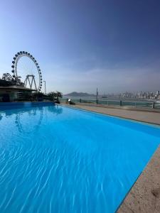 uma grande piscina azul com uma roda gigante ao fundo em Studio Pé na Areia II em Balneário Camboriú