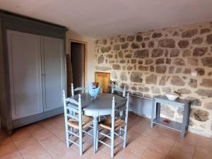comedor con mesa, sillas y pared de piedra en L'Ostel Aveyronnais, en Golinhac