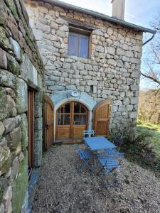una casa de piedra con una mesa y sillas delante de ella en L'Ostel Aveyronnais, en Golinhac