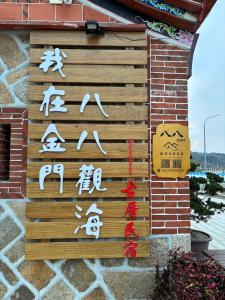 um sinal com escrita asiática numa parede de tijolos em Ba Ba Guan Hai Ancient House B&B em Jinsha