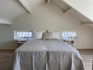 Cama grande en habitación con 2 ventanas en Villa Alba, Walcheren, en Gapinge