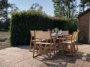 una mesa de madera con sillas y copas de vino. en Villa Alba, Walcheren, en Gapinge
