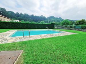 ein Pool in einem Garten mit grünem Gras in der Unterkunft Romántico apartamento con terraza y piscina in Villabáñez