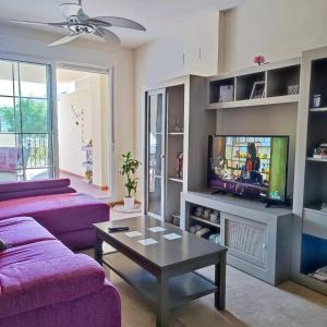 een woonkamer met paarse banken en een tv bij Residencial Vereda Golf in Roquetas de Mar
