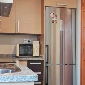 een keuken met een roestvrijstalen koelkast en een magnetron bij Residencial Vereda Golf in Roquetas de Mar