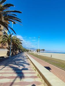 een stoep naast het strand met palmbomen bij Residencial Vereda Golf in Roquetas de Mar