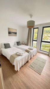 two beds in a white room with two windows at Les terrasses de la vallée - Esneux (Liège) in Méry