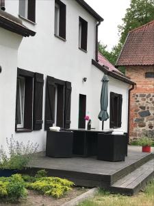 a white house with black windows and an umbrella at Folwark Mazurskie Legendy - Azyl dla Dorosłych in Kruklanki