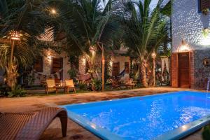 una piscina davanti a una casa con palme di Pousada Villa Coqueiro a Luis Correia