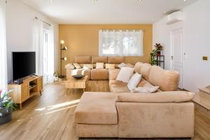ein Wohnzimmer mit einem Sofa und einem TV in der Unterkunft Villa Le Verger 15 minutes de Faro in Estói