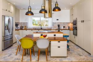 eine Küche mit einem Holztisch und gelben Stühlen in der Unterkunft Villa Le Verger 15 minutes de Faro in Estói