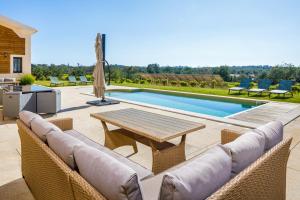 eine Terrasse mit einem Tisch, Stühlen und einem Pool in der Unterkunft Villa Le Verger 15 minutes de Faro in Estói