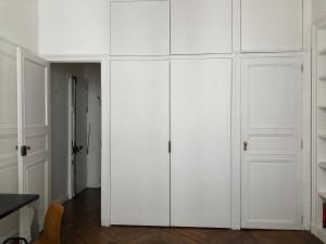 einen weißen Schrank mit weißen Türen in einem Zimmer in der Unterkunft Beautiful studio in the heart of Le Marais in Paris