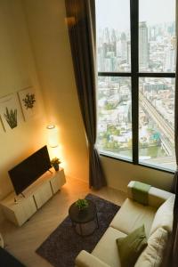 a living room with a couch and a large window at On Nut Duplex with City Views, 5-minute Walk to BTS, Ideal Long Stays in Bangkok