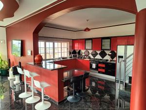 a kitchen with red cabinets and bar stools at Casa Miami in Tarrafal