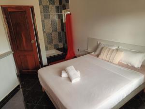 1 dormitorio con 1 cama blanca y 2 toallas en Casa Miami, en Tarrafal