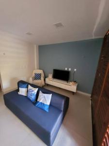uma sala de estar com um sofá azul e uma televisão em Casa em condomínio de Cotovelo c/ vista para o mar em Parnamirim
