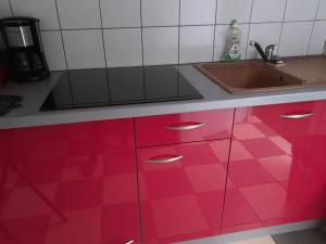 a kitchen with red cabinets and a sink at Le Refuge in Saint-Leu +24 photos