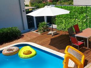 a swimming pool with a table and an umbrella at Gumla House in Stara Novalja