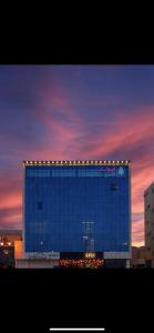 Arica hotel apartments في تبوك: مبنى أزرق كبير مع أضواء عليه