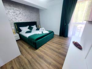 a bedroom with a green bed with a white flower on it at Anastasia Luxury Apartment in Sinaia