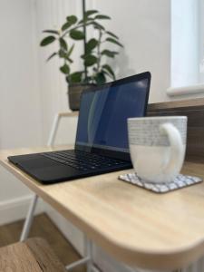 a laptop computer sitting on a table with a cup of coffee at Swan Lake Lodge & free parking in Cardiff