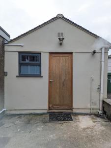 a white garage with a wooden door and a window at Swan Lake Lodge & free parking in Cardiff